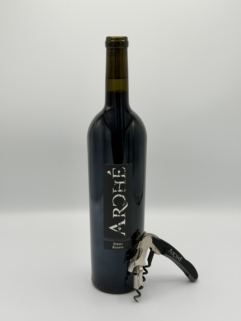 bottle of wine with corkscrew leaning against it.