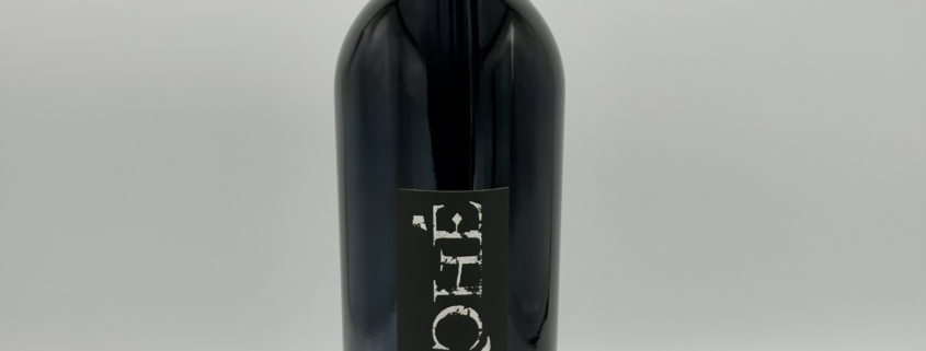 bottle of wine with corkscrew leaning against it.